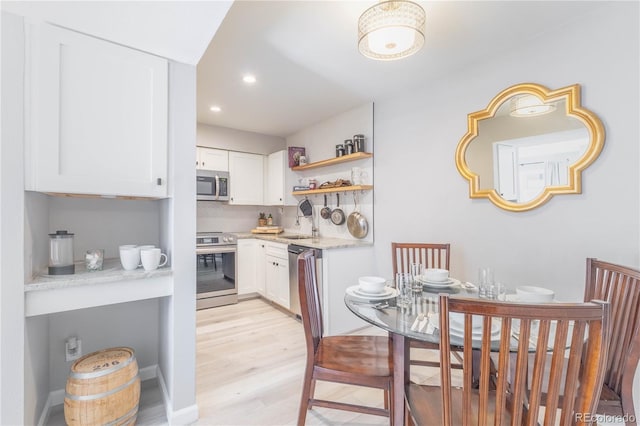 kitchen featuring white cabinets, tasteful backsplash, stainless steel appliances, and light hardwood / wood-style flooring