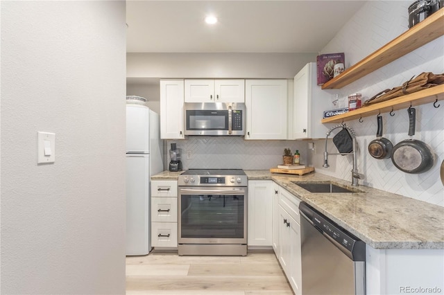 kitchen with white cabinets, sink, light stone countertops, tasteful backsplash, and stainless steel appliances