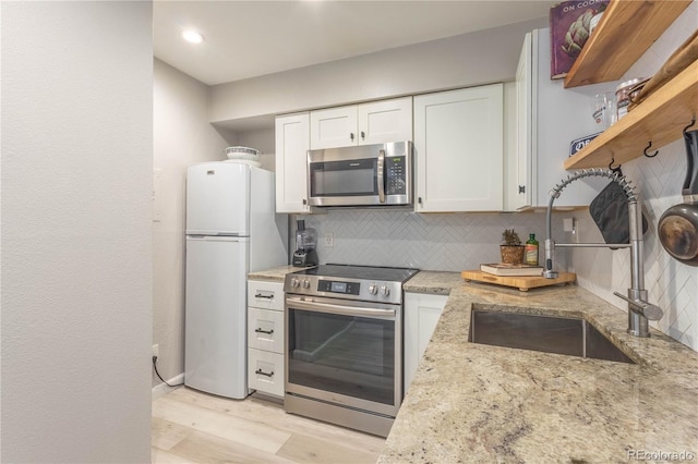 kitchen with white cabinets, sink, tasteful backsplash, light stone counters, and stainless steel appliances