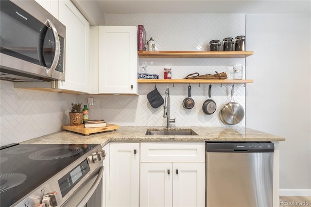 kitchen featuring light stone countertops, appliances with stainless steel finishes, backsplash, sink, and white cabinets