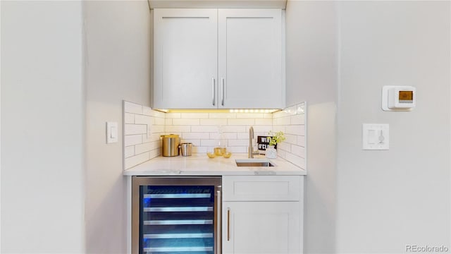 bar featuring wine cooler, white cabinetry, sink, and backsplash