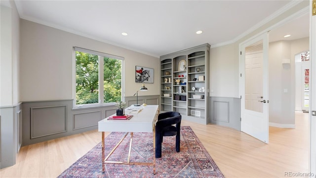 office area with ornamental molding, light wood-type flooring, and built in shelves