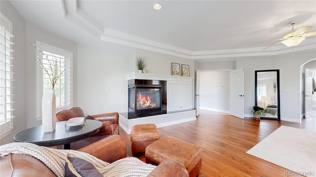 living room with a raised ceiling, a tile fireplace, plenty of natural light, and hardwood / wood-style floors