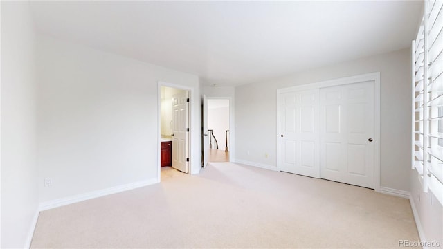 unfurnished bedroom with connected bathroom, light colored carpet, and a closet