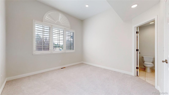 unfurnished bedroom featuring ensuite bathroom and light carpet