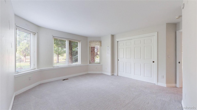 unfurnished bedroom with light carpet and a closet