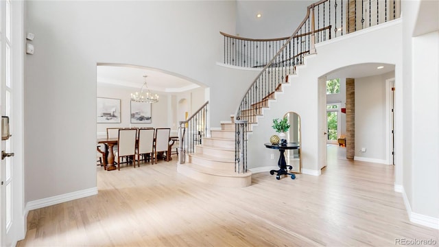 entryway featuring light hardwood / wood-style flooring, a chandelier, and a high ceiling