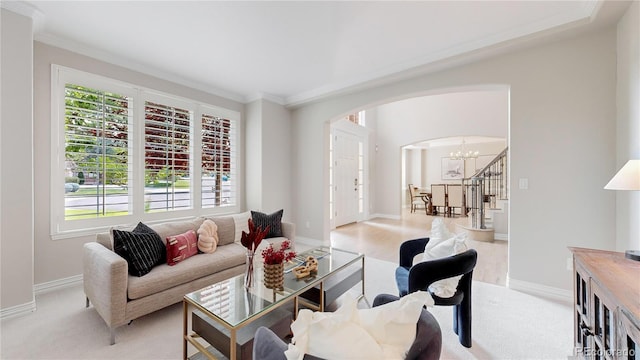 carpeted living room featuring ornamental molding and an inviting chandelier