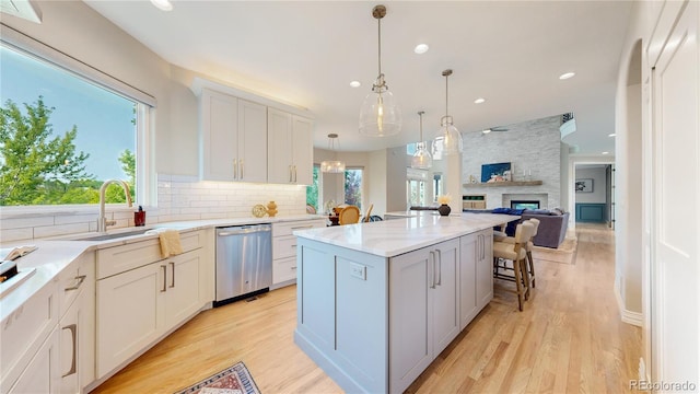 kitchen featuring a kitchen island, a wealth of natural light, decorative light fixtures, white cabinets, and stainless steel dishwasher