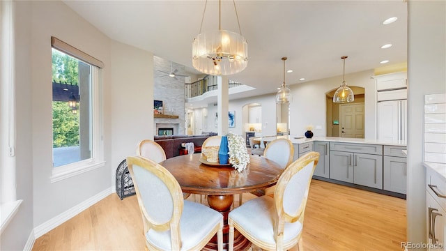 dining area featuring ceiling fan, a fireplace, and light hardwood / wood-style flooring