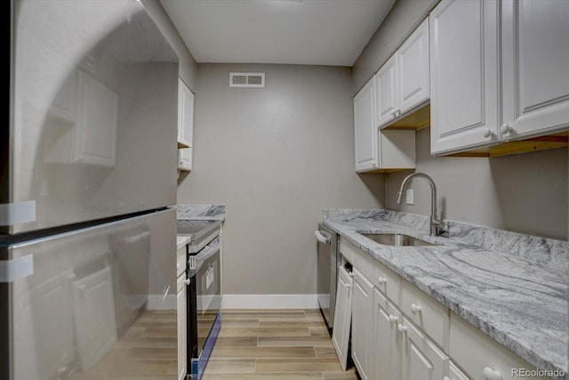 kitchen with visible vents, appliances with stainless steel finishes, light wood-type flooring, white cabinetry, and a sink