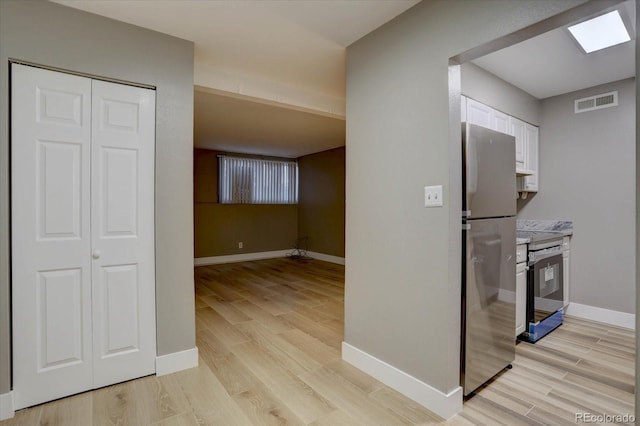 interior space with light wood finished floors, appliances with stainless steel finishes, visible vents, and white cabinetry