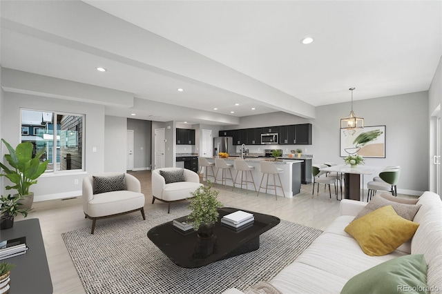 living area featuring light wood finished floors, visible vents, baseboards, and recessed lighting