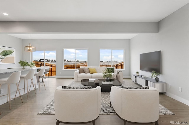 living area with an inviting chandelier, light wood-style flooring, baseboards, and recessed lighting