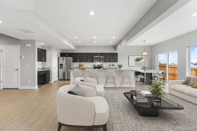 living area with light wood-type flooring, baseboards, and recessed lighting