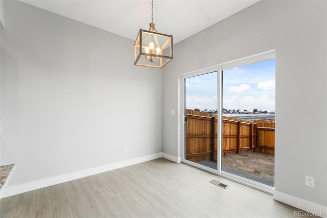 interior space featuring a notable chandelier, visible vents, baseboards, and wood finished floors