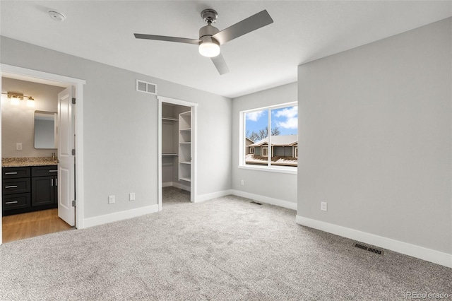 unfurnished bedroom featuring light carpet, visible vents, and a walk in closet