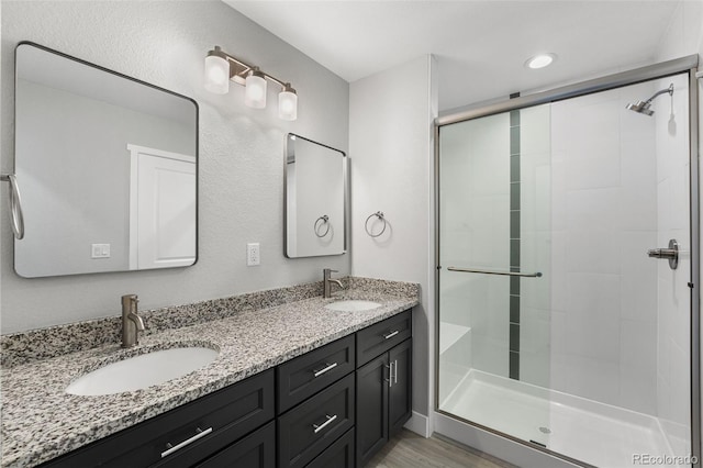 full bathroom with double vanity, a sink, and a shower stall