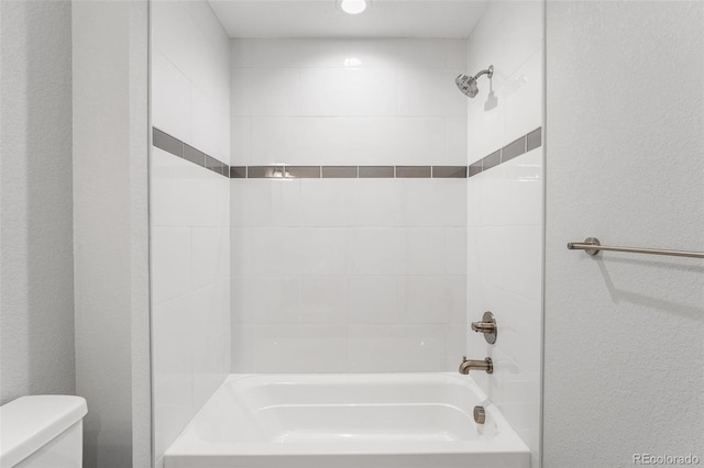 bathroom featuring a textured wall,  shower combination, and toilet