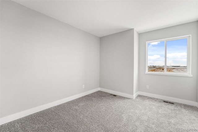 empty room with carpet, visible vents, and baseboards