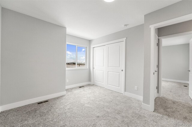 unfurnished bedroom featuring light carpet, a closet, visible vents, and baseboards