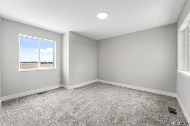 carpeted empty room featuring visible vents and baseboards