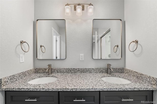 full bath featuring double vanity, an enclosed shower, and a sink