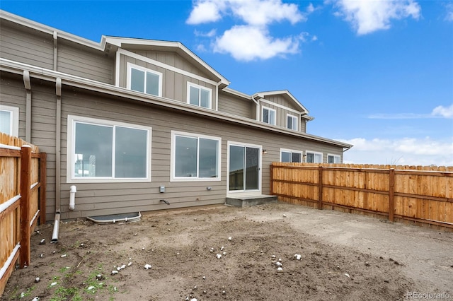 rear view of house with board and batten siding and a fenced backyard