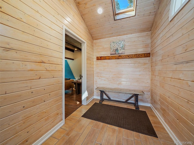 corridor with lofted ceiling with skylight, wooden walls, and light wood-style floors