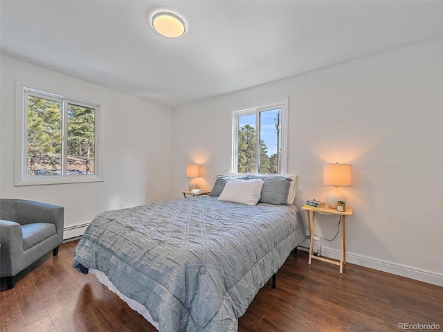 bedroom with wood finished floors, baseboards, and baseboard heating