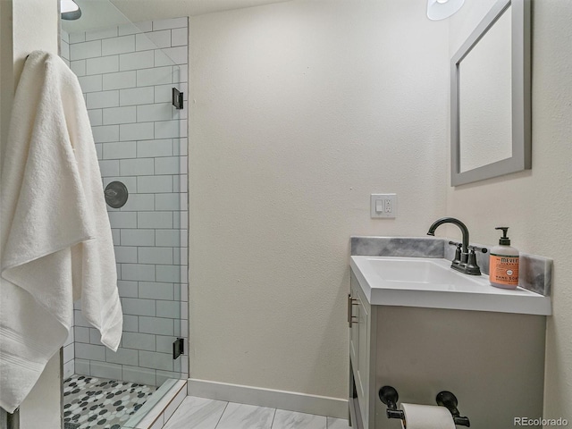 bathroom featuring baseboards, a stall shower, and vanity