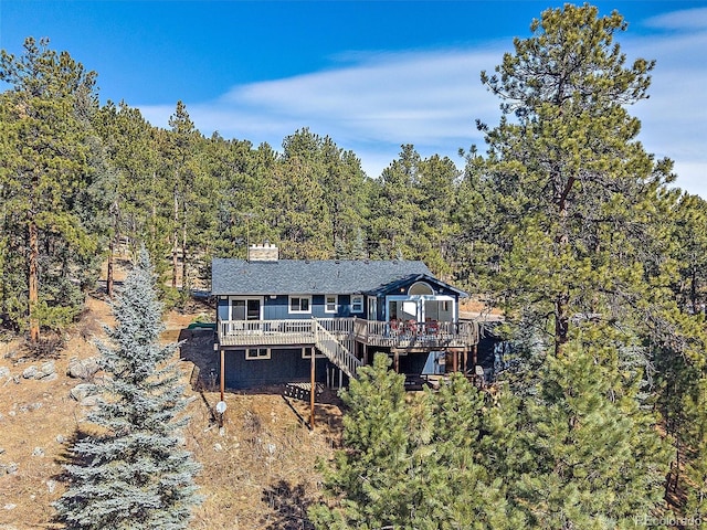 back of house with a deck, stairway, a forest view, and a chimney