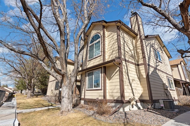 view of property exterior featuring a chimney and central AC