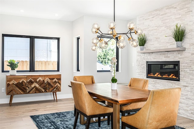 dining area featuring a fireplace, baseboards, and wood finished floors