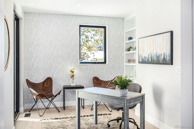 office area featuring baseboards, wood finished floors, visible vents, and wallpapered walls