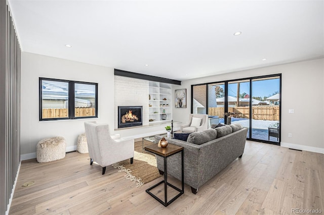 living area with light wood finished floors, a fireplace, recessed lighting, and baseboards