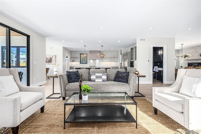 living room with light wood-type flooring, recessed lighting, visible vents, and baseboards