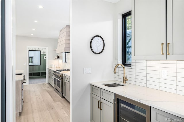 kitchen featuring beverage cooler, range with two ovens, gray cabinets, and a sink