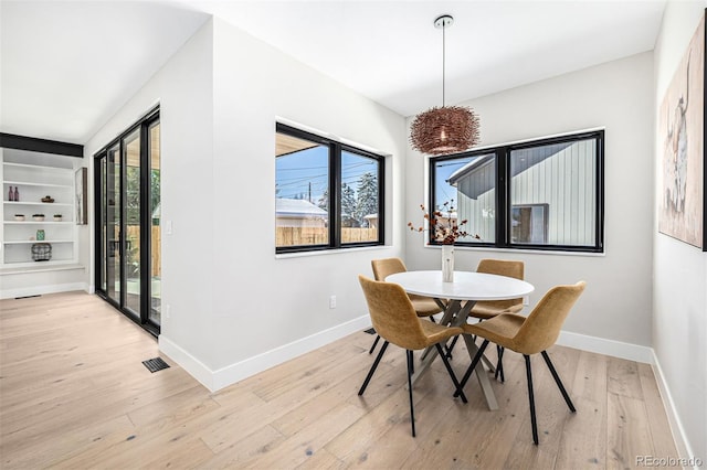 dining space with light wood-style floors, visible vents, and baseboards