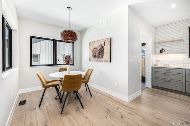 dining room featuring light wood-style floors, baseboards, and visible vents