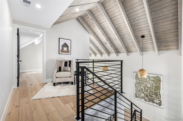 corridor featuring vaulted ceiling with beams, hardwood / wood-style flooring, visible vents, baseboards, and an upstairs landing