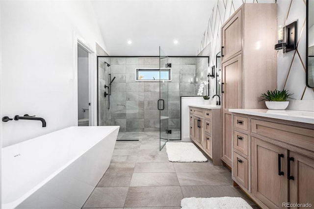 bathroom with a stall shower, toilet, a soaking tub, vanity, and recessed lighting