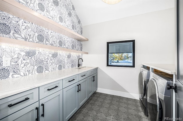 washroom with baseboards, cabinet space, a sink, and washing machine and clothes dryer