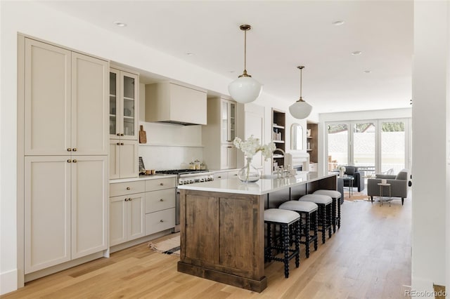 4131 Quivas St, Denver, CO 80211 - kitchen featuring high end stove, light wood-style flooring, custom exhaust hood, an island with sink, and a kitchen breakfast bar