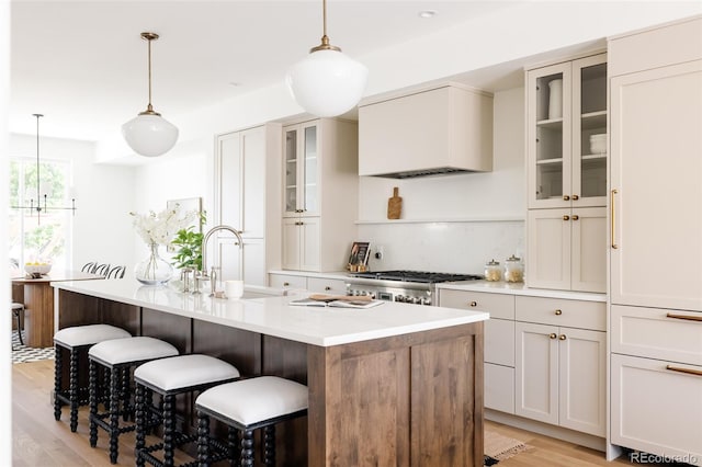 4131 Quivas St, Denver, CO 80211 - kitchen featuring custom exhaust hood, light wood-style flooring, a center island with sink, light countertops, and a breakfast bar area