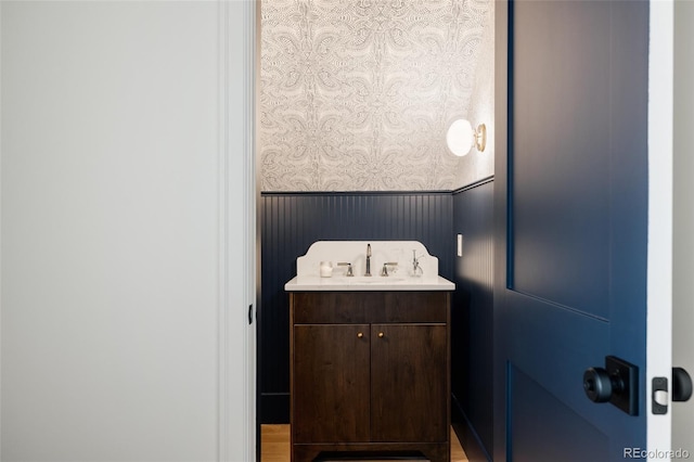 4131 Quivas St, Denver, CO 80211 - bathroom featuring a wainscoted wall, wallpapered walls, vanity, and wood finished floors