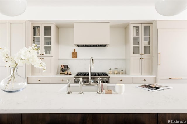 4131 Quivas St, Denver, CO 80211 - kitchen featuring exhaust hood, light stone countertops, and glass insert cabinets