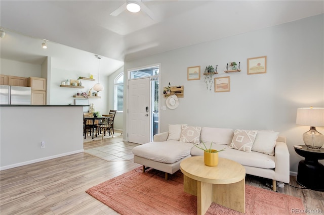 living room with vaulted ceiling, baseboards, a ceiling fan, and light wood finished floors