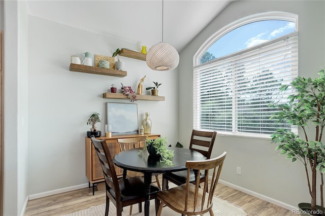 dining area with baseboards, light wood-style flooring, and lofted ceiling