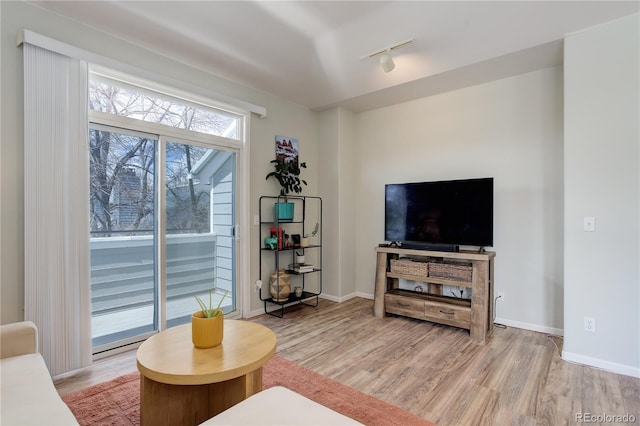 living room featuring baseboards, rail lighting, and light wood-type flooring